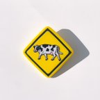 作品《牛横断注意》標識ブローチ