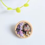 作品【絵画のような木製ブローチ】ブランコで揺れるシナモン文鳥さんと紫のお花。つまみ細工。