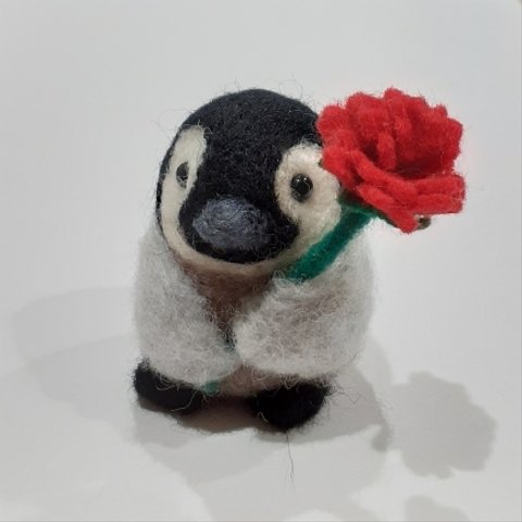 羊毛フェルトのカーネーションを持つペンギンの赤ちゃん