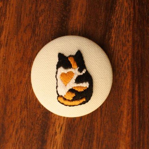 「ちょこんと座る三毛猫のみーちゃん」の刺繍くるみボタンマグネット(b)