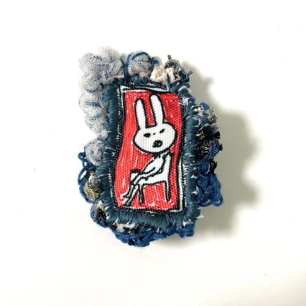 赤い壁画にいるウサギのブローチ